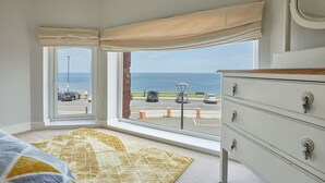 A room with a large window offering a view of the sea and parking area. - Host & Stay | Sunset View (Whitby)