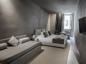 A modern hotel room with a large bed, a sofa, a small table, and a TV. - Elysium Suites Collection (Rome)