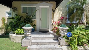 A hotel entrance with a black awning, a white door, and steps leading up to it. - Villa Venezia BB (Miami Beach)