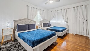A bedroom with two beds, a ceiling fan, and white curtains. - Villa Venezia BB (Miami Beach)