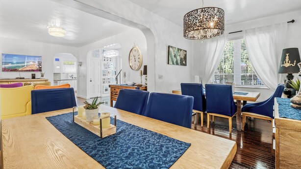 A spacious dining area with a wooden table, blue patterned rug, and blue upholstered chairs. - Villa Venezia BB (Miami Beach)