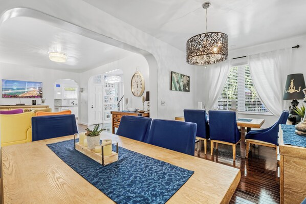 A spacious dining area with a wooden table, blue patterned rug, and blue upholstered chairs. - Villa Venezia BB (Miami Beach)