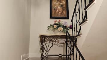 A staircase with a black railing, a clock, and a framed artwork above it.