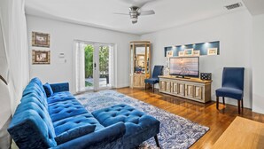 A living room with a blue sofa, a wooden cabinet, and a television. - Villa Venezia BB (Miami Beach)