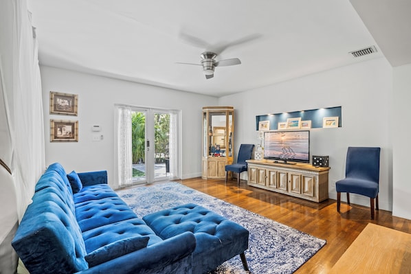 A living room with a blue sofa, a wooden cabinet, and a television. - Villa Venezia BB (Miami Beach)