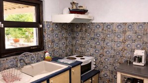 A kitchen with a sink, stove, microwave, and a small table with a toaster. - Blue Seaside Retreat - Fully Equipped Garden Gem (Chrani)