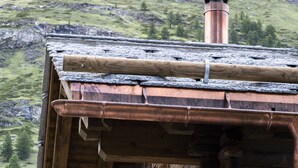 A rustic log cabin with a chimney, wooden windows, and a stone foundation. - Chalet Eggen (Zermatt)