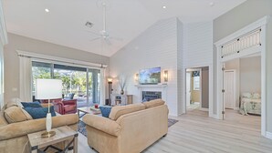 Ein großzügiges Wohnzimmer mit Kamin, Deckenventilator und einem großen Fenster.