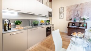 A modern kitchen with a central island, a dining area with a wooden table, and a large abstract painting on the wall.