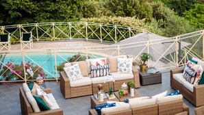 A terrace with wicker furniture, a pool, and a view of a mountainous landscape. - CASOLARE DEI COLLI Panoramic Private Pool, Lavish Interiors and a Gourmet Kitchen (Camaiore)