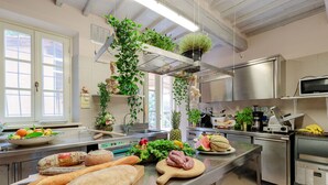 A kitchen with stainless steel appliances, a wooden cutting board with food, and hanging plants. - CASOLARE DEI COLLI Panoramic Private Pool, Lavish Interiors and a Gourmet Kitchen (Camaiore)