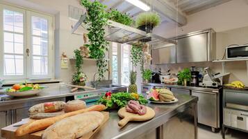 A kitchen with stainless steel appliances, a wooden cutting board with food, and hanging plants.