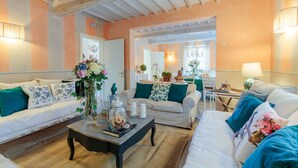 A cozy living room with two sofas, a coffee table, and a dining area with a table and chairs. - CASOLARE DEI COLLI Panoramic Private Pool, Lavish Interiors and a Gourmet Kitchen (Camaiore)