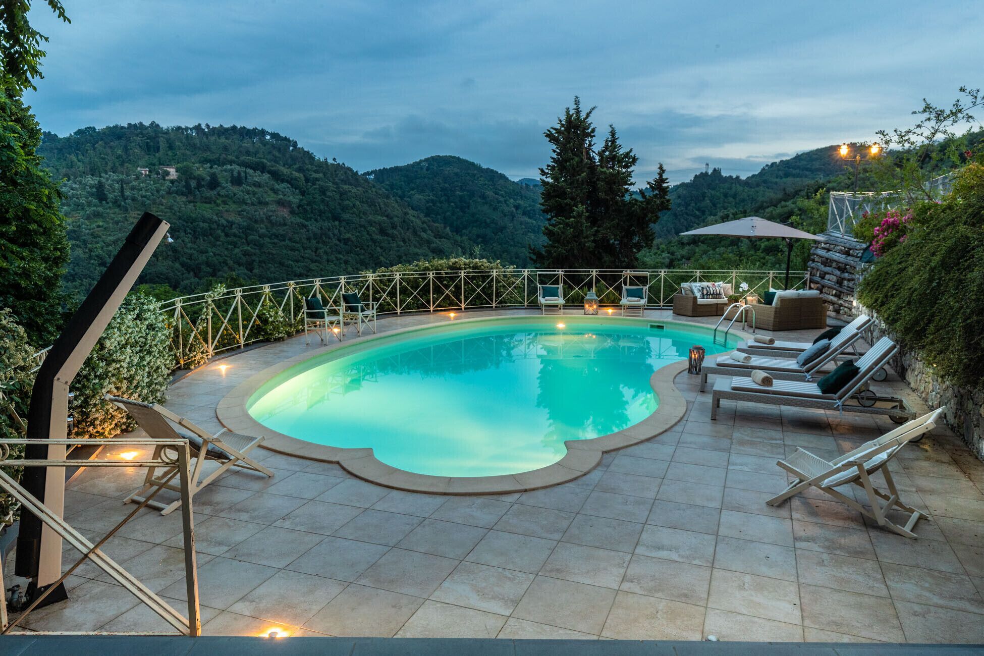 A swimming pool with a curved edge, surrounded by lounge chairs and a wooden deck.