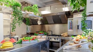 A commercial kitchen with stainless steel appliances, fresh produce, and hanging plants. - CASOLARE DEI COLLI Panoramic Private Pool, Lavish Interiors and a Gourmet Kitchen (Camaiore)