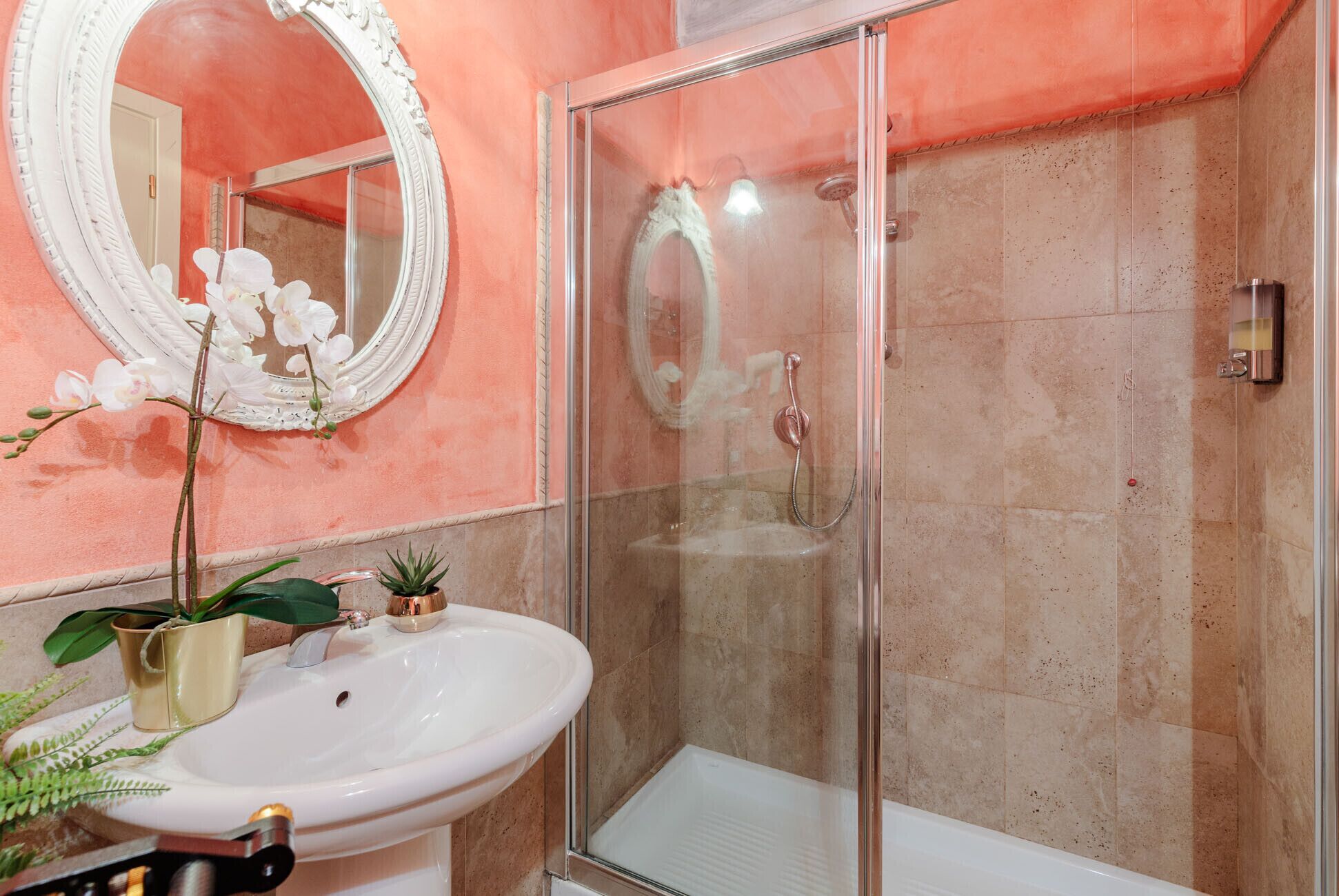 Ein Badezimmer mit einer begehbaren Glasdusche, einem weißen Waschbecken und einem großen Spiegel.