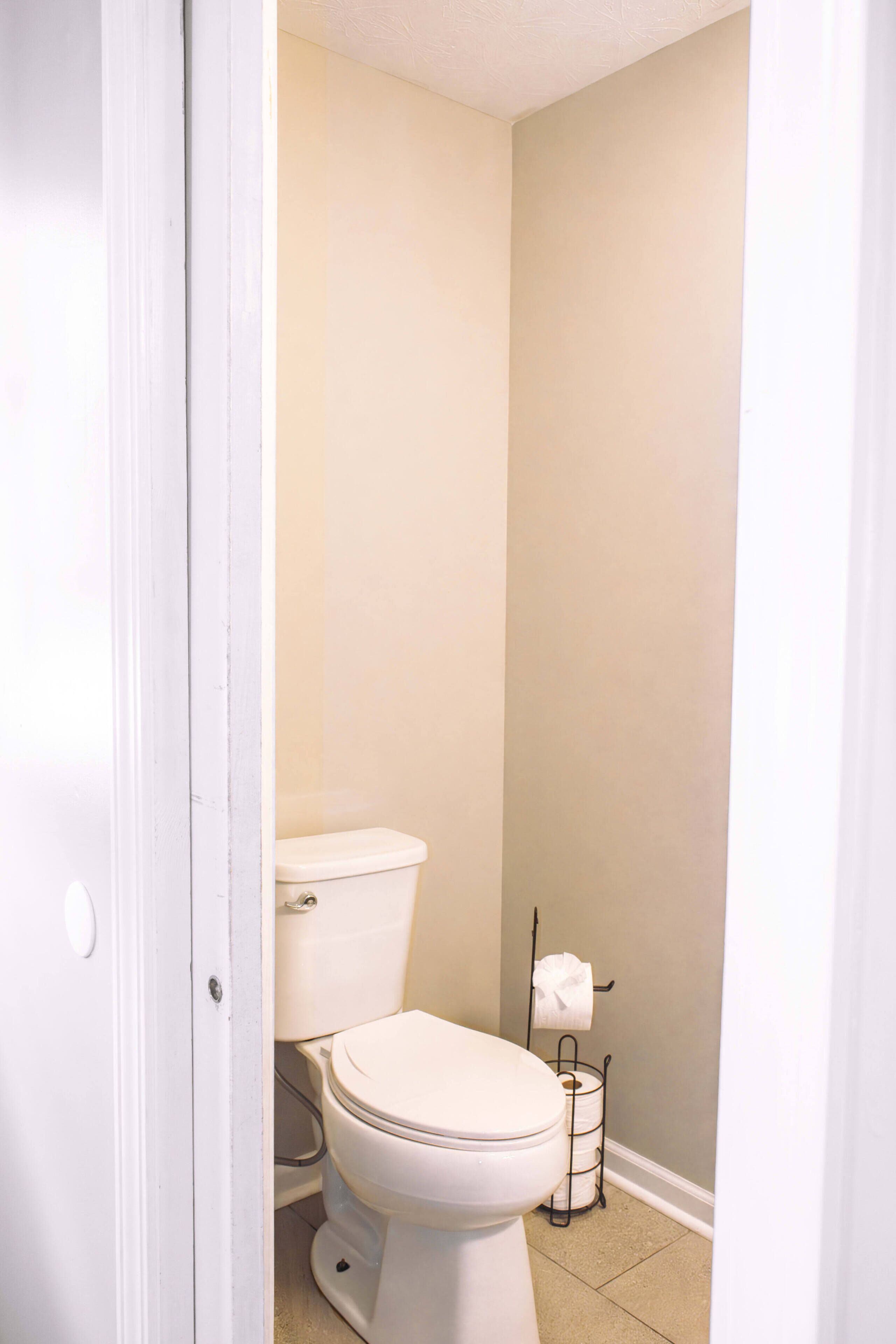 Ein kleines, schmales Badezimmer mit Toilette, Toilettenpapier und einem Handtuchhalter.