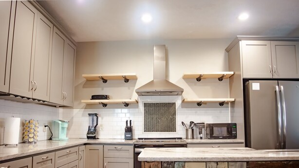 A kitchen with beige cabinets, a stainless steel refrigerator, a microwave, and a blender.