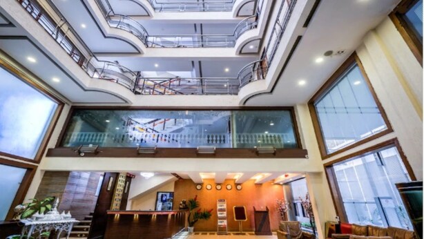 A multi-level atrium with glass railings, a reception desk, and seating areas. - Golden Metro Hotel (Bengaluru)