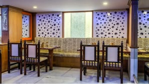 A dining area with wooden chairs and a patterned sofa. - Golden Metro Hotel (Bengaluru)