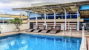 A rooftop swimming pool with lounge chairs and a pergola. - Golden Metro Hotel (Bengaluru)