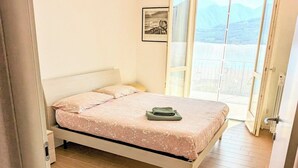 A bedroom with a bed, a window, and a door.