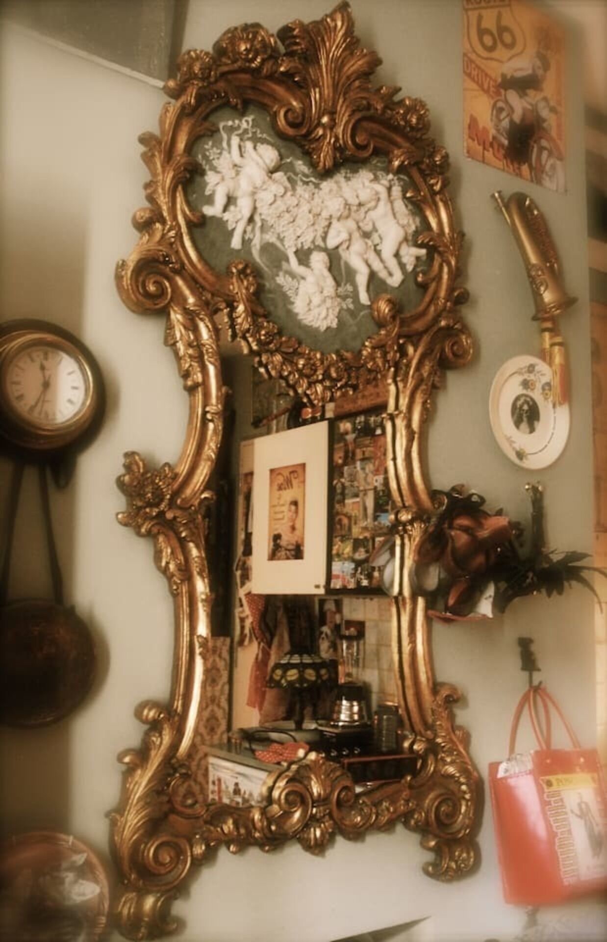 A wall with a large ornate mirror, a clock, and various decorative items.
