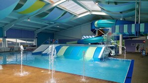 Ein großer Indoor-Wasserpark mit Schwimmbecken, Wasserrutschen und einer Wellenmaschine.