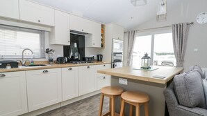 Eine moderne Küche mit weißen Schränken, einer Holz Arbeitsplatte und zwei hölzernen Barhocker.