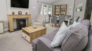 Ein Wohnzimmer mit Kamin, einer Couch, einem Couchtisch und einem an der Wand befestigten Fernseher.