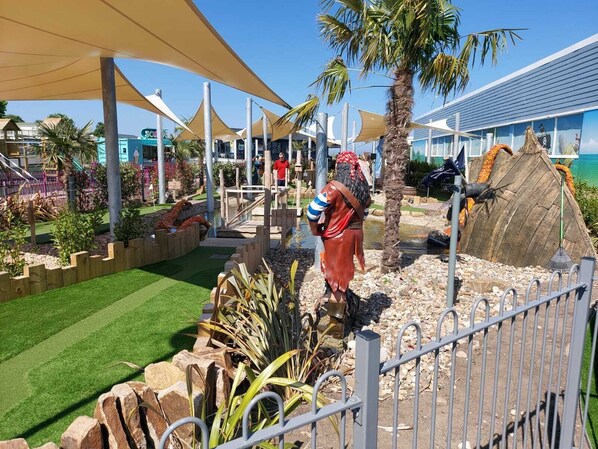 Zona turística con piscina, palmeras y un bar tiki.