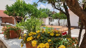 A garden with potted plants and flowers, a pool, and a building with a tiled roof. - House with pool (Pompei)