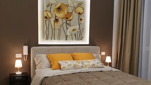 A bedroom with a bed, two bedside lamps, a wall-mounted phone, and a framed floral artwork above the bed. - House with pool (Pompei)