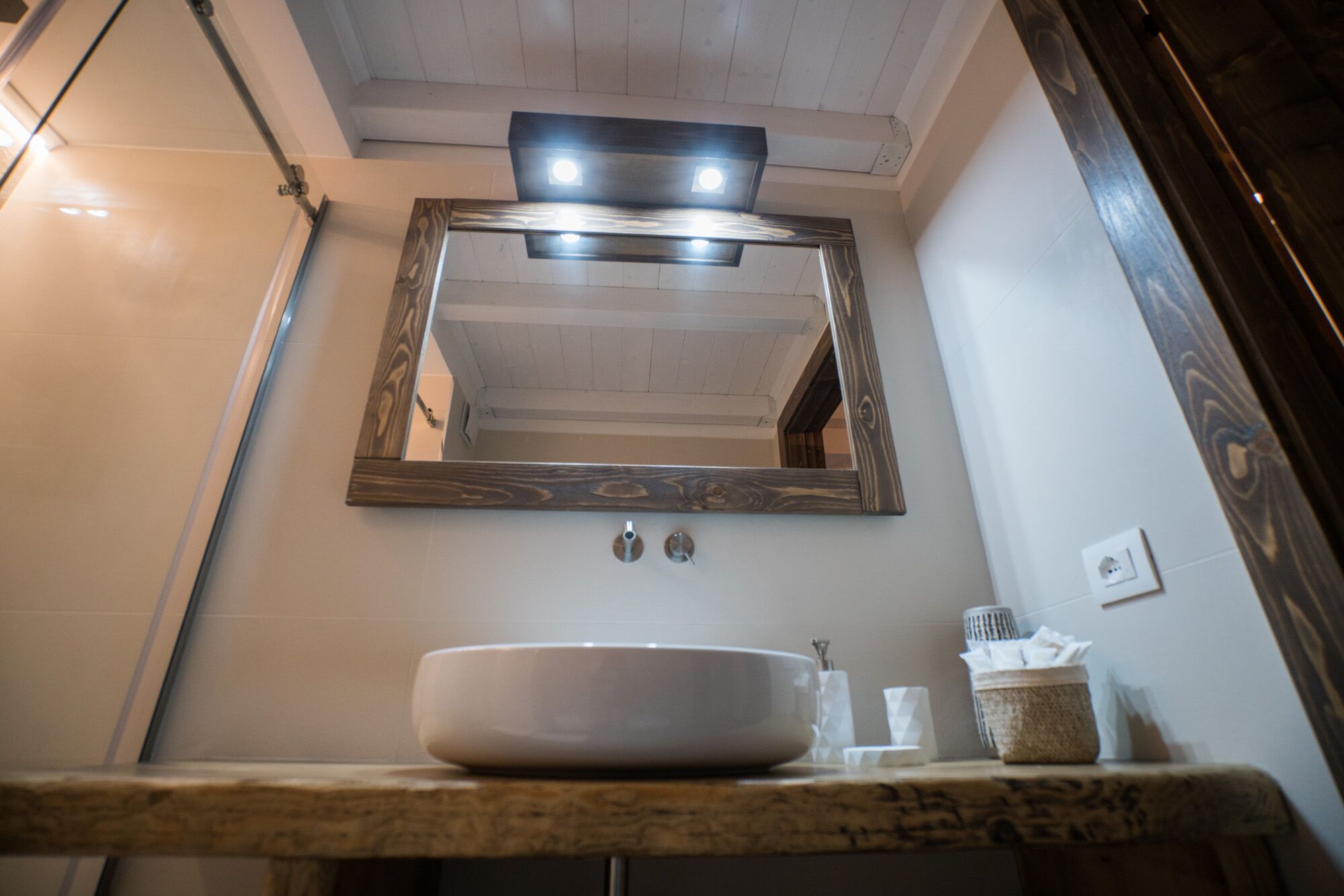 A bathroom with a wooden-framed mirror, a white sink, and a towel dispenser.