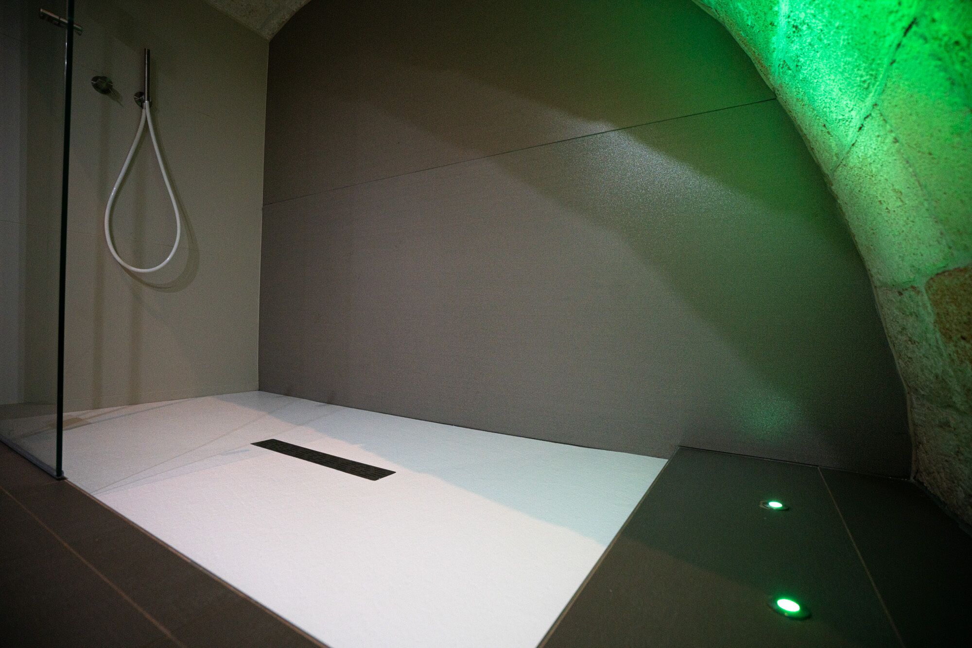 Ein minimalistisches Badezimmer mit Dusche, einem wei ßen Waschbecken und grüner Beleuchtung.