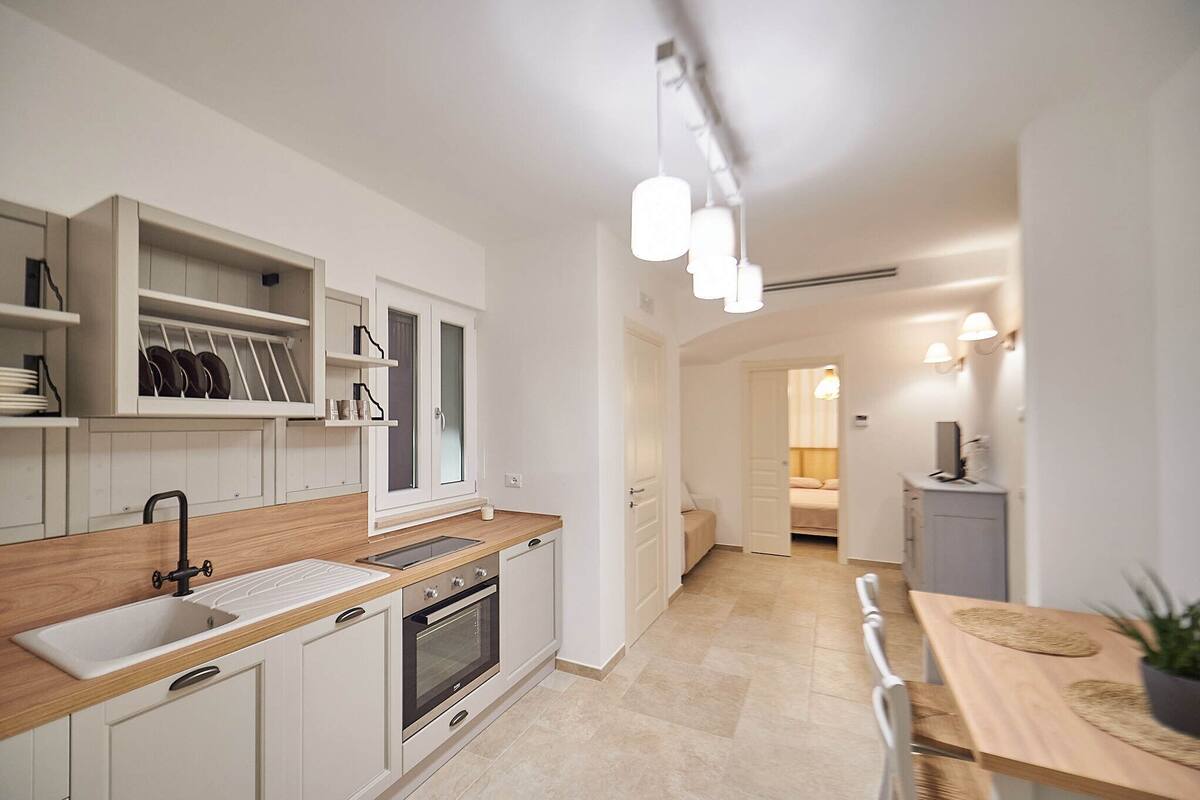 Eine moderne Küche mit weißen Schränken, einer Holz Arbeitsplatte und einem eingebauten Ofen. Ein Essbereich mit Holztisch und Stühlen ist ebenfalls vorhanden.