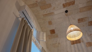 Una habitación con techo de ladrillo, una ventana con cortinas y una lámpara colgante de fibras.
