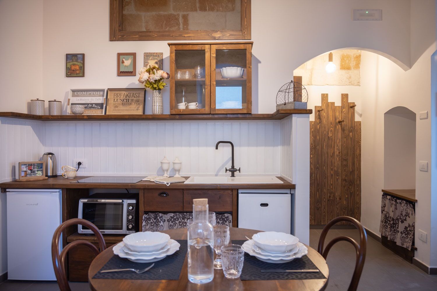 Una cocina compacta con un mueble de madera, un lavamanos y una mesa de comedor para cuatro.