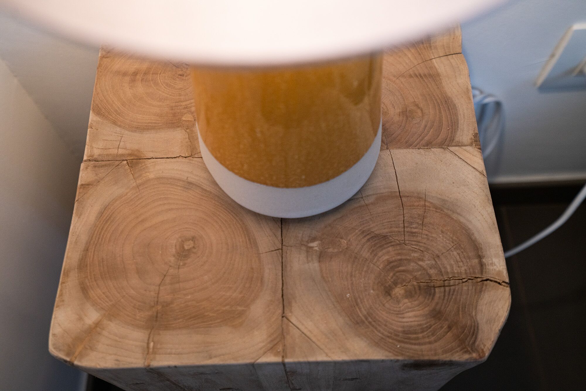 A table lamp on a wooden block with visible grain patterns.