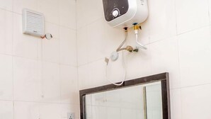 A bathroom with a white sink, a mirror, and a wall-mounted heater. - Kedros Precious Suites (Ilorin)