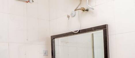 Un baño con lavamanos blanco, un espejo y un calentador de pared.