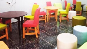 A room with multiple round tables and colorful chairs, arranged in a casual layout. - Kedros Precious Suites (Ilorin)