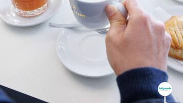 Impostazione per la colazione con diversi cibi, tra cui un bicchiere di succo d'arancia, una tazza di caffè e diverse ciotole di frutta.