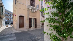 A narrow street with buildings on either side, featuring a building with a balcony and a door with shutters. - Mest Michè by Polignando (Polignano a Mare)