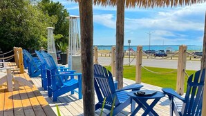 A wooden deck with blue chairs and tables, overlooking a beach and ocean. - Paradise Inn On The Beach (Saugeen Shores)