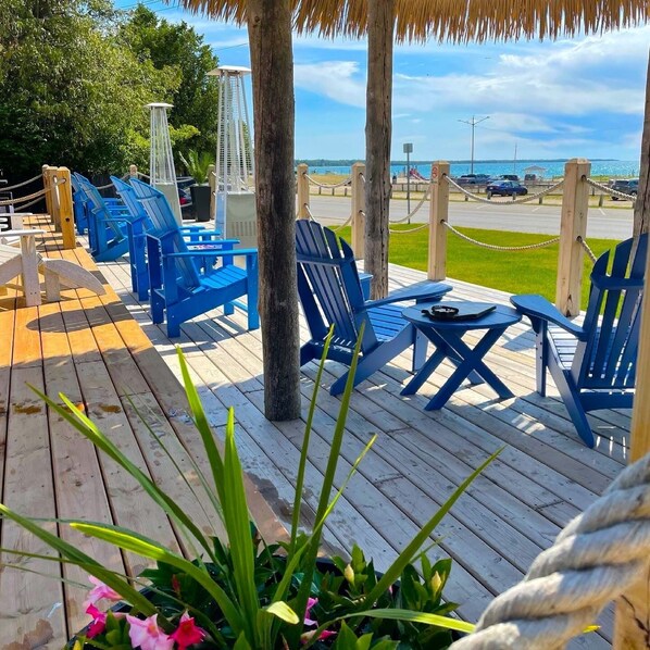 A wooden deck with blue chairs and tables, overlooking a beach and ocean. - Paradise Inn On The Beach (Saugeen Shores)