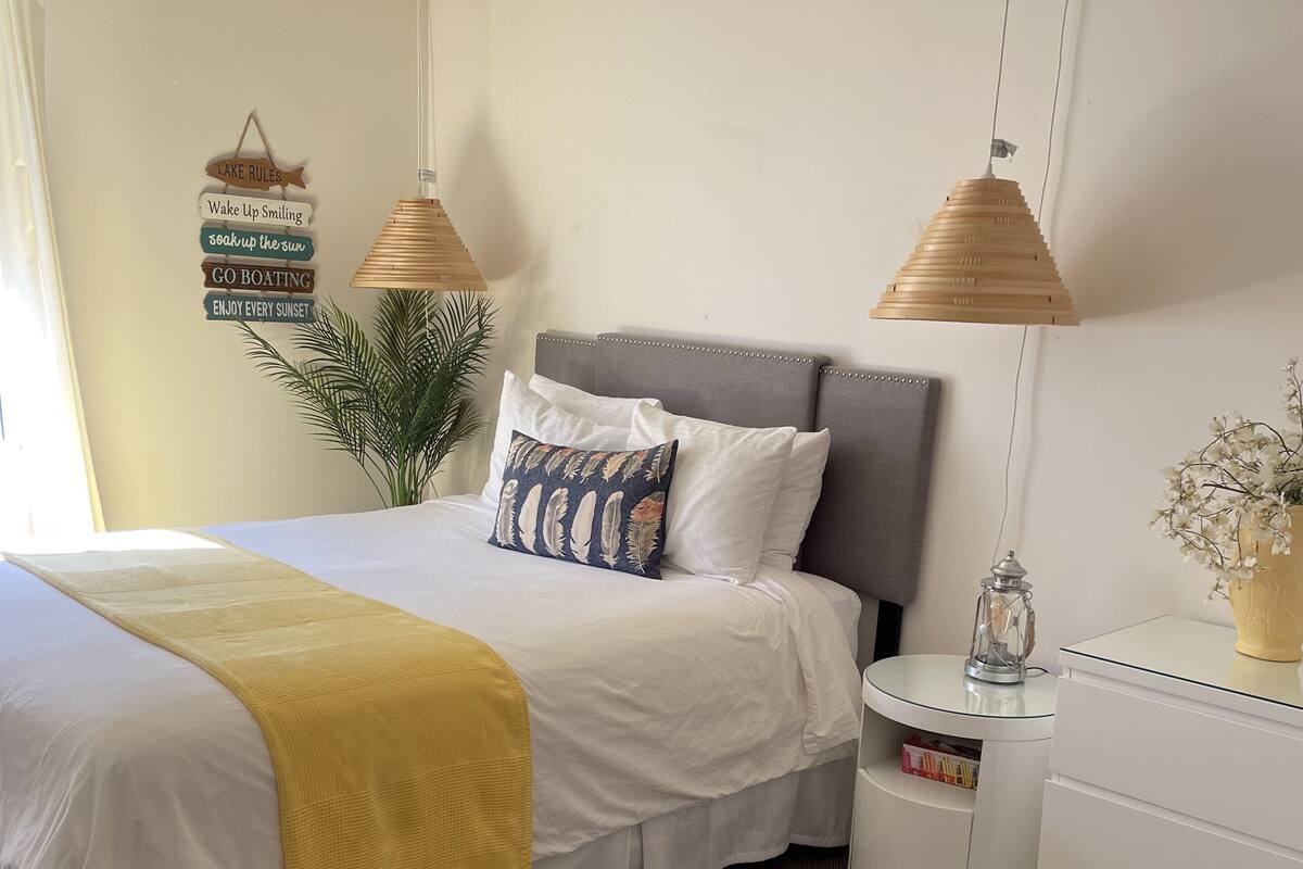 A neatly arranged bedroom with a bed, bedside table, and a nightstand.