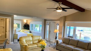 A spacious living room with a ceiling fan, two sofas, a coffee table, and a view of the outside. - Paradise Inn On The Beach (Saugeen Shores)
