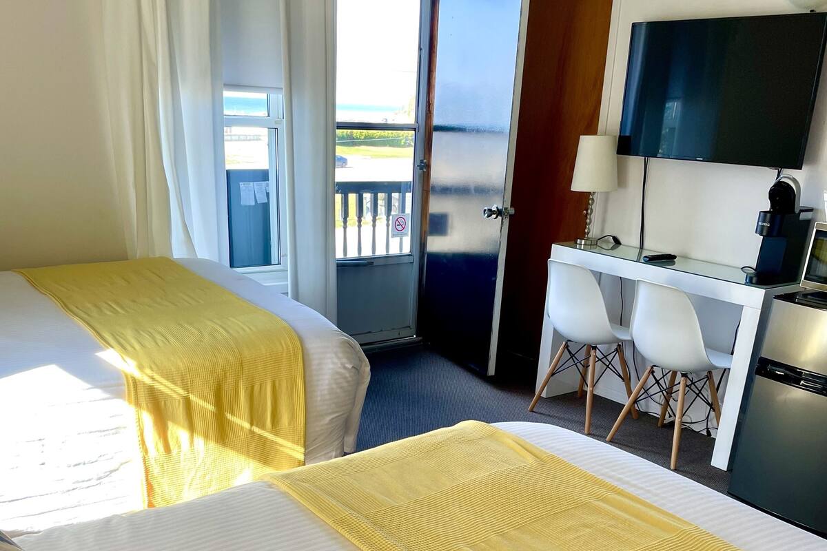 A hotel room with two beds, a desk, and a TV.