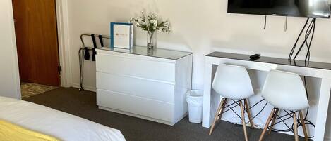Habitación de hotel con dos camas, un escritorio con silla, un televisor y un cuadro en la pared.